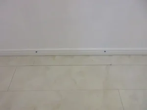 床材（塩ビタイル）を貼り戻し、木巾木を取り付けたら補修が終わりです。