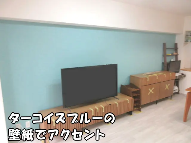 リビングの壁一面をターコイズブルーの壁紙でアクセントにした様子